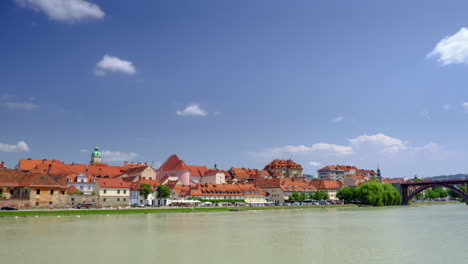 Maribor,-Slovenia-with-Drava-river-waterfront-Lent-on-a-sunny-day,-time-lapse-of-rolling-clouds-in-the-sky