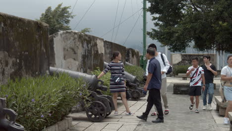 Turistas-Que-Pasan-Cerca-De-Viejos-Cañones-De-Artillería-De-Metal-En-La-Cima-De-Fortaleza-Do-Monte-En-Macao,-Sar-De-Macao,-China