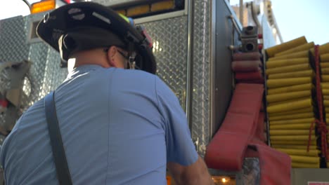 Feuerwehrmann-Arbeitet-Am-Frühen-Morgen-An-Ausrüstung-Und-Feuerwehrschläuchen-An-Einem-Feuerwehrauto,-Um-Sich-Auf-Notfallmaßnahmen-Vorzubereiten
