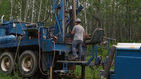 Water-well-drilling-rig-operator-connecting-drilling-bit-on-drilling-platform-in-slow-motion