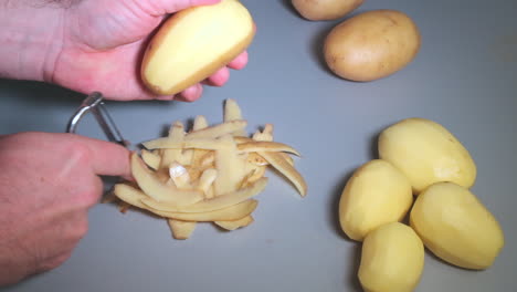 Slow-motion-of-male-hands-peeling-potatoes-with-kitchen-peeler,-man-at-domestic-work,-cooking