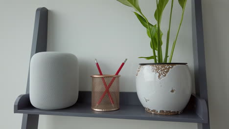 Tiro-Estático-En-Cámara-Lenta-Del-Hombre-Tocando-Dos-Veces-Un-Homepod-De-Apple-En-La-Parte-Superior-De-La-Estantería-De-Aspecto-Moderno-Adyacente-A-Un-Portalápices---Planta