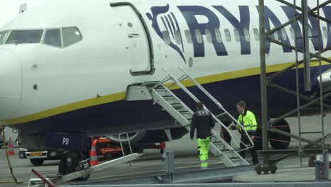 Workers-in-yellow-jackets-next-to-a-plane's-stairs