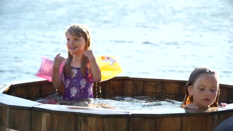 4-jähriges-Mädchen-Im-Einhorn-Badeanzug,-Das-Im-Heißen-Außenpool-Am-See-Glücklich-Aussieht,-Sommer-In-Skandinavien