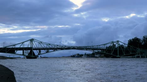 Beautiful-fast-moving-dark-gray-rain-clouds-over-the-Oskara-Kalpaka-swing-bridge-in-Liepaja-city-in-evening,-wide-shot