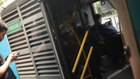 An-Indonesian-woman-getting-off-a-public-bus-with-a-mask-over-her-mouth-to-prevent-the-spread-of-any-sickness-or-disease