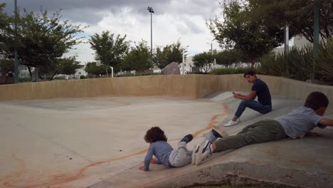 Niño-Deslizándose-Hacia-Abajo-En-Una-Rampa-De-Hormigón-En-El-Parque-Saki-En-Un-Día-Muy-Nublado