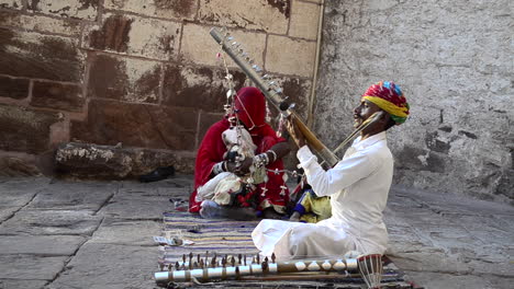 Traditional-Folk-singer-signing-song-performing-playing-violin-in-public-with-his-family-daylight-outdoor-side-view