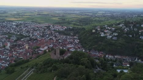 Volando-Sobre-El-Castillo-De-Strahlenburg-En-La-Ciudad-Alemana-De-Schriesheim-Con-Vista-Aérea-Del-Valle-Y-La-Ciudad-Durante-La-Puesta-De-Sol