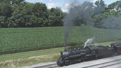 Luftaufnahme-Einer-Alten-Dampfmaschine-Mit-Personenwagen,-Die-Entlang-Der-Amish-Landschaft-Schnaufen