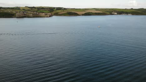 Drone-footage-of-a-SUP-boarder-on-a-blue-river-with-waves-and-Charles-Fort-with-green-hills-in-the-background