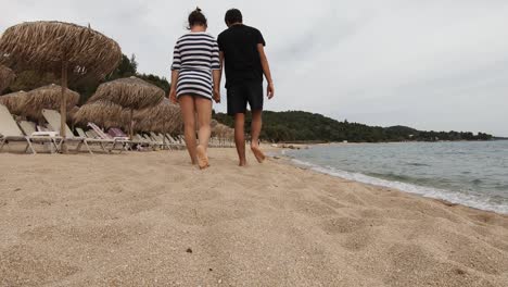 Pareja-Caminando-En-La-Orilla-De-La-Playa,-Tomados-De-La-Mano