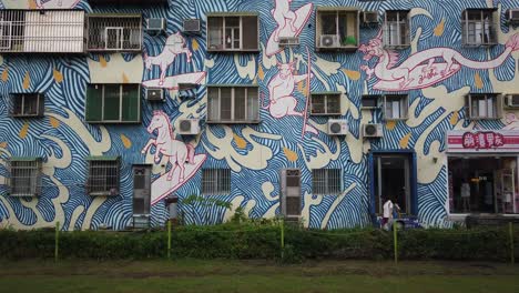 Un-Tren-Lrt-Que-Pasa-Por-Un-Mural-De-Arte-Callejero-En-El-Distrito-De-Arte-Pier-2-En-Kaohsiung,-Taiwán