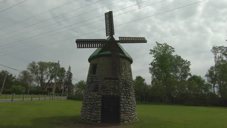 View-of-windmill,-mill,-in-natural-green-park,-grass-and-trees-and-beautiful-cloudy-sky