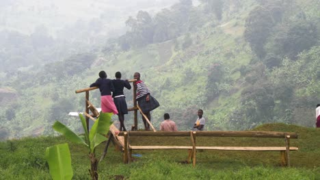 Eine-Gruppe-Afrikanischer-Kinder-Auf-Einer-Klippe,-Die-In-Ein-Grünes-Tal-Im-Ländlichen-Uganda-Starrt