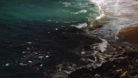 Static-shot-of-dirty-ocean-water-with-trash-and-plastic-crashing-against-shore