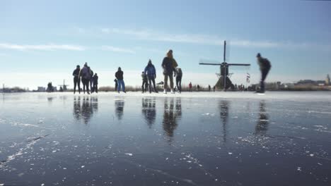 Dutch-locals-ice-skating-on-frozen-canals-in-polder-land-near-windmills