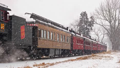 An-Antique-Restored-Steam-Engine-With-Passenger-Cars-Approaches-in-a-Snow-Storm