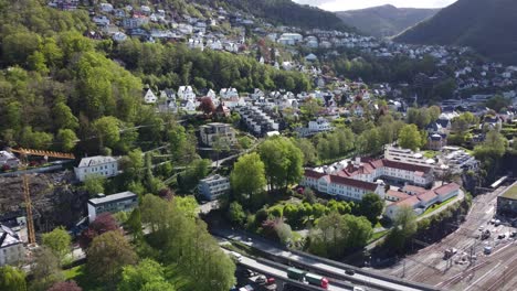 Expensive-neighbourhood-Kalfaret-and-Fjellsiden-in-Bergen-Norway---Passing-road-E39-and-Bergensbanen-railway-watching-Floyfjellet---Aerial