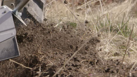 Rototiller-working-on-topsoil-in-Sweden,-agriculture,-slow-motion-close-up