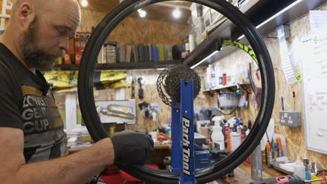 Mecánico-De-Bicicletas-Masculino-Corrige-Una-Rueda-En-Un-Taller