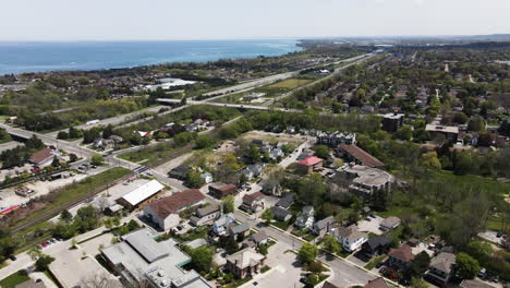 Aerial-flyover-Grimsby-City-with-traffic-on-highway-and-blue-Lake-Ontario-in-background