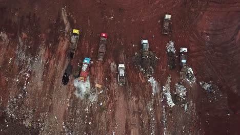 Straight-down-aerial-view-of-dump-trucks-unloading-garbage-at-a-landfill