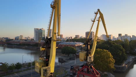 Aerial-rising-shot-revealing-two-old-port-cranes-in-Puerto-Madero-docks,-Buenos-Aires