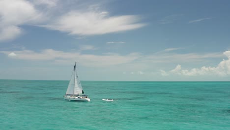 Sailboat-With-Connected-Motorboat-in-Turquoise-Caribbean-Sea,-Drone-Aerial-View