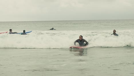 Young-female-surfing-on-cloudy-day-in-Portugal-Algarve-on-small-wave-in-Atlantic-Ocean