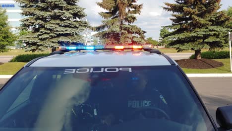 Offizier-Im-Polizeiauto-Mit-Blauen-Und-Roten-Lichtern,-Die-Tagsüber-In-Mississauga,-Kanada,-Oben-Blinken---Nahaufnahme
