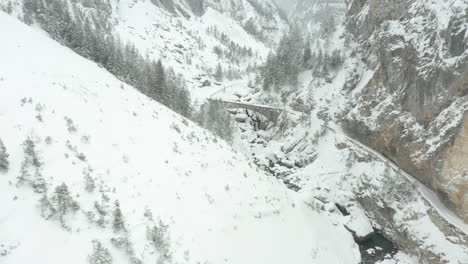 Aerial-of-stone-bridge-over-small-river-in-snow-covered-landscape