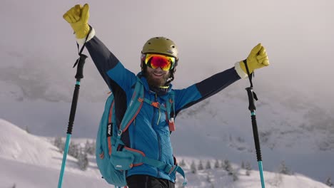 Successful-skier-man-raise-arms-in-achievement-on-snow-mountain