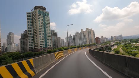 Seoul-Traffic---Driver's-POV-car-exits-from-Cheongdam-Bridge-goes-to-Gangbyeonbuk-ro-expressway-near-Han-river,-Lotte-Tower-on-background-Seoul,-Korea,-Jun-27,-2021-summer-day-cloudy,-slip-road