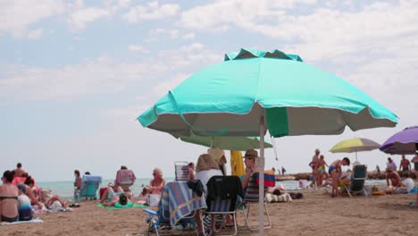 Crowded-sea-beach-with-tourist-people-sunbathing-in-Alcossebre,-Spain