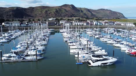 Luxury-yachts-and-sailboats-moored-in-Conwy-marina-mountain-waterfront-aerial-view-North-Wales-slow-rising