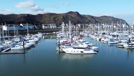 Luxury-yachts-and-sailboats-moored-in-Conwy-marina-mountain-waterfront-aerial-left-low-dolly-view-North-Wales