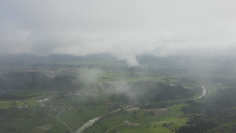 Drone-appears-out-of-thick-mist,-reveals-green-landscape-of-Bled,-Slovenia