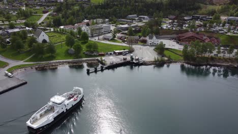 Electric-ferry-named-Kinsarvik-is-arriving-town-of-Kinsarvik-in-Hardangerfjord-Ullensvang---Beautiful-sunny-day-aerial-of-ferry-from-company-Boreal-approaching-ferry-pier