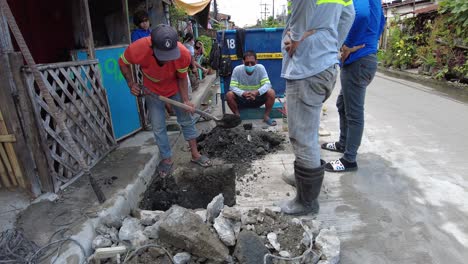 Los-Capataces-Que-Vestían-Chalecos-Reflectantes-De-Seguridad-Utilizaron-Su-Pala,-Mezcla-De-Cemento-Y-Un-Martillo-De-Demolición-Para-Realizar-Una-Excavación-Junto-A-La-Cuneta-Del-Camino-Para-Instalar-Nuevas-Tuberías-De-Agua-Desde-La-Línea-De-Agua-Principal.