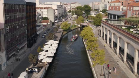 Moliceiros,-tradicional-boasts,-with-tourists-enjoying-the-canals-of-Ria-de-Aveiro,-Portugal