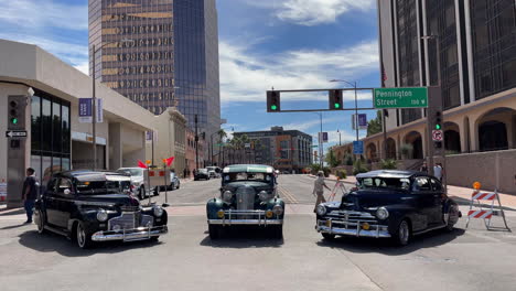 Drei-Lowrider-Bomben-Oldtimer-Werden-Beim-Tucson-Meet-Yourself-Festival-Mit-Einem-Südlichen-Kirchengebäude-Im-Hintergrund-Ausgestellt