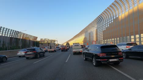 Seoul-multilane-expressway---cars-stuck-in-a-traffic-jam-in-the-highway-at-sunset-busy-hour---driver's-POV,-noise-reduction-barriers-to-protect-city-from-car's-pollution-and-reduce-the-noise-levels