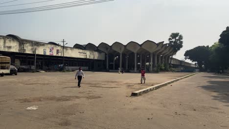 Blick-Hinter-Den-Bahnhof-Kamalapur-Leerer-Parkplatz-Und-Seitliche-Zufahrtsstraße-Mit-Menschen,-Die-In-Dhaka-Vorbeigehen