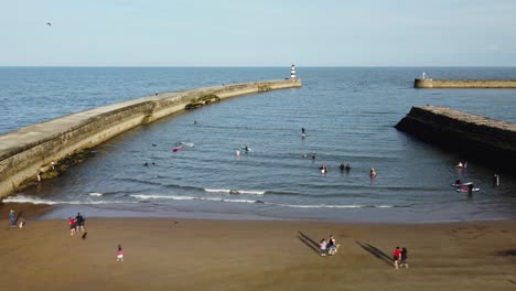 Gente-Divirtiéndose-En-La-Playa-Y-Nadando-En-El-Mar,-Vista-Panorámica-Aérea-De-La-Entrada-Del-Puerto-En-Un-Día-Soleado-Durante-El-Verano