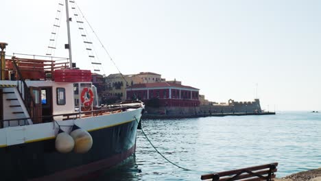 Barco-Antiguo-Histórico-En-Chania-Creta,-Vista-Histórica-Escénica-Sobre-El-Puerto-De-La-Ciudad-Vieja-Frente-Al-Mar-Griego,-Turistas-Haciendo-Turismo-En-Un-Día-Soleado-De-Verano-En-Grecia