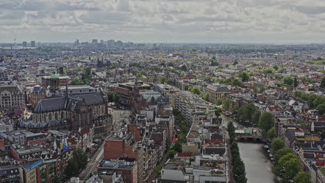 Amsterdam-Netherlands-Aerial-v7-panoramic-view-capturing-cityscape-across-grachtengordel-and-binnenstad-neighborhoods,-birds-eye-view-looking-at-busy-dam-square-and-national-monument---August-2021