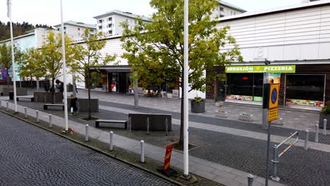 Centro-De-Bergsjön,-Suecia--Lapso-De-Tiempo-De-Movimiento-De-Una-Vista-De-La-Calle-Cerca-De-Un-Centro-Comercial-En-El-Corazón-Del-Distrito-De-Bergsjön-En-Suecia-Con-Automóviles-Y-Personas-Que-Pasan-Durante-El-Día