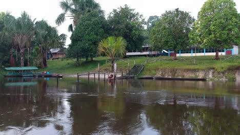 Girl-on-jetty-brushes-teeth-in-to-Amazon-river-on-an-overcast-day