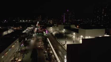 Miami-night-traffic-below,-parkade-rooftop-exercise-class-above